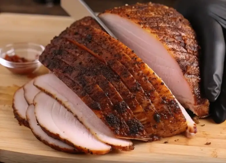 Chef slicing smoked turkey breast on a wooden board, revealing juicy meat and a seasoned, crispy crust.