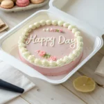 Bento cake with pastel frosting in a takeout box, decorated with a simple buttercream message.